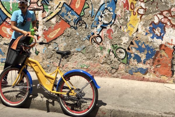 Gids van Free biking tours staat bij geel blauwe fiets in Cartagena.